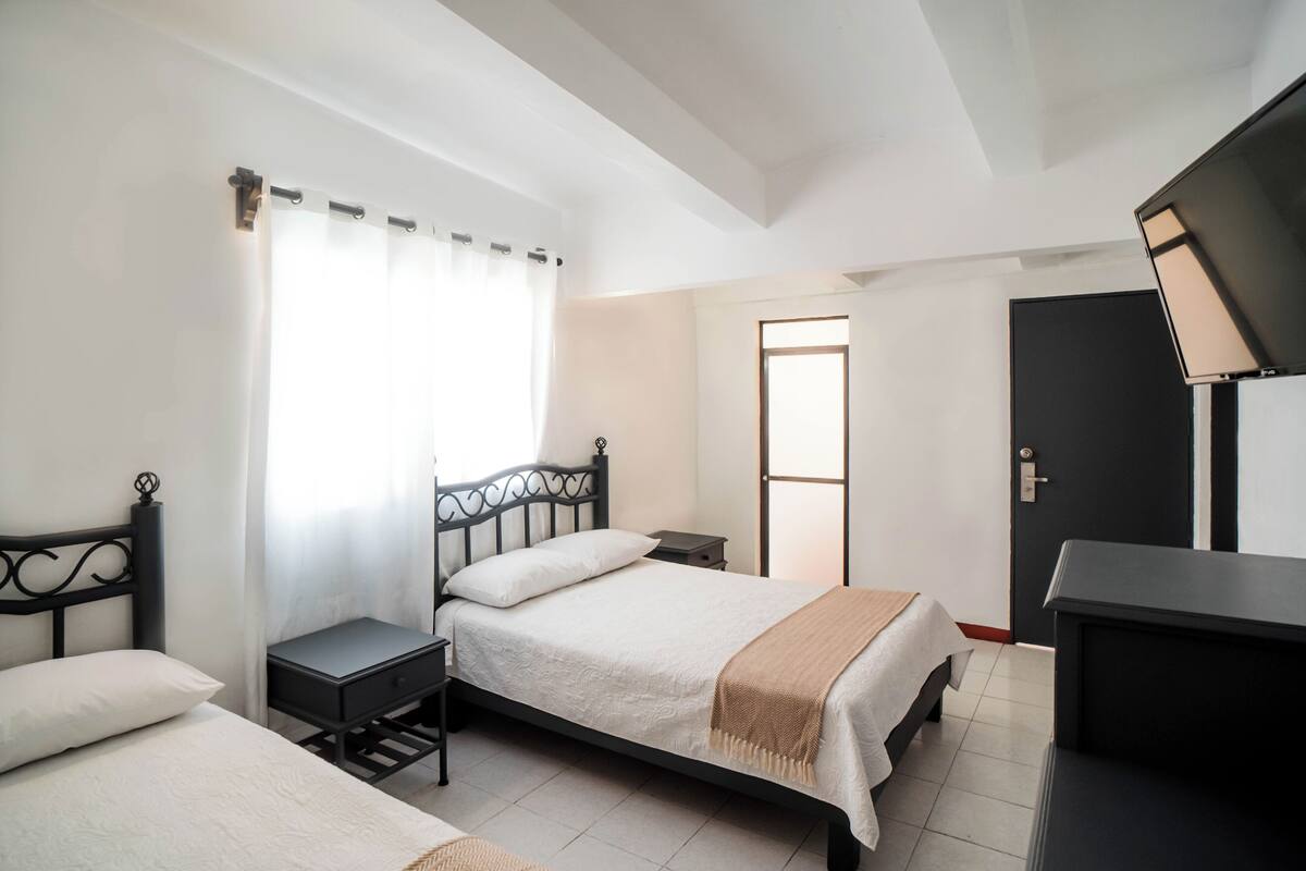 A bedroom with a bed, bedside tables, a desk, and a wardrobe.