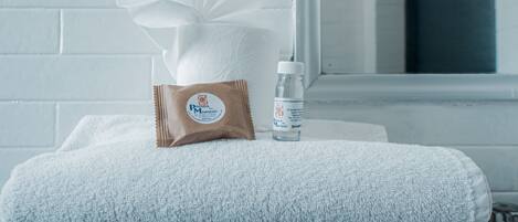 A bathroom with a white towel, a tissue, and a bottle of shampoo on a white towel.