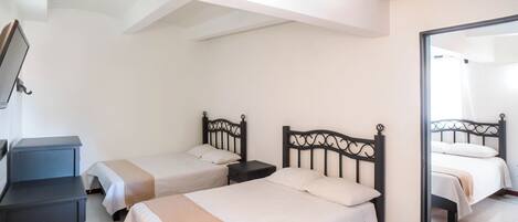 Quarto com duas camas, uma escrivaninha e um espelho.