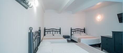 A bedroom with two beds, a dresser, and a wall-mounted TV.