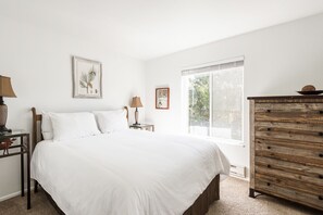 A bedroom with a large bed, a wooden dresser, and two nightstands.