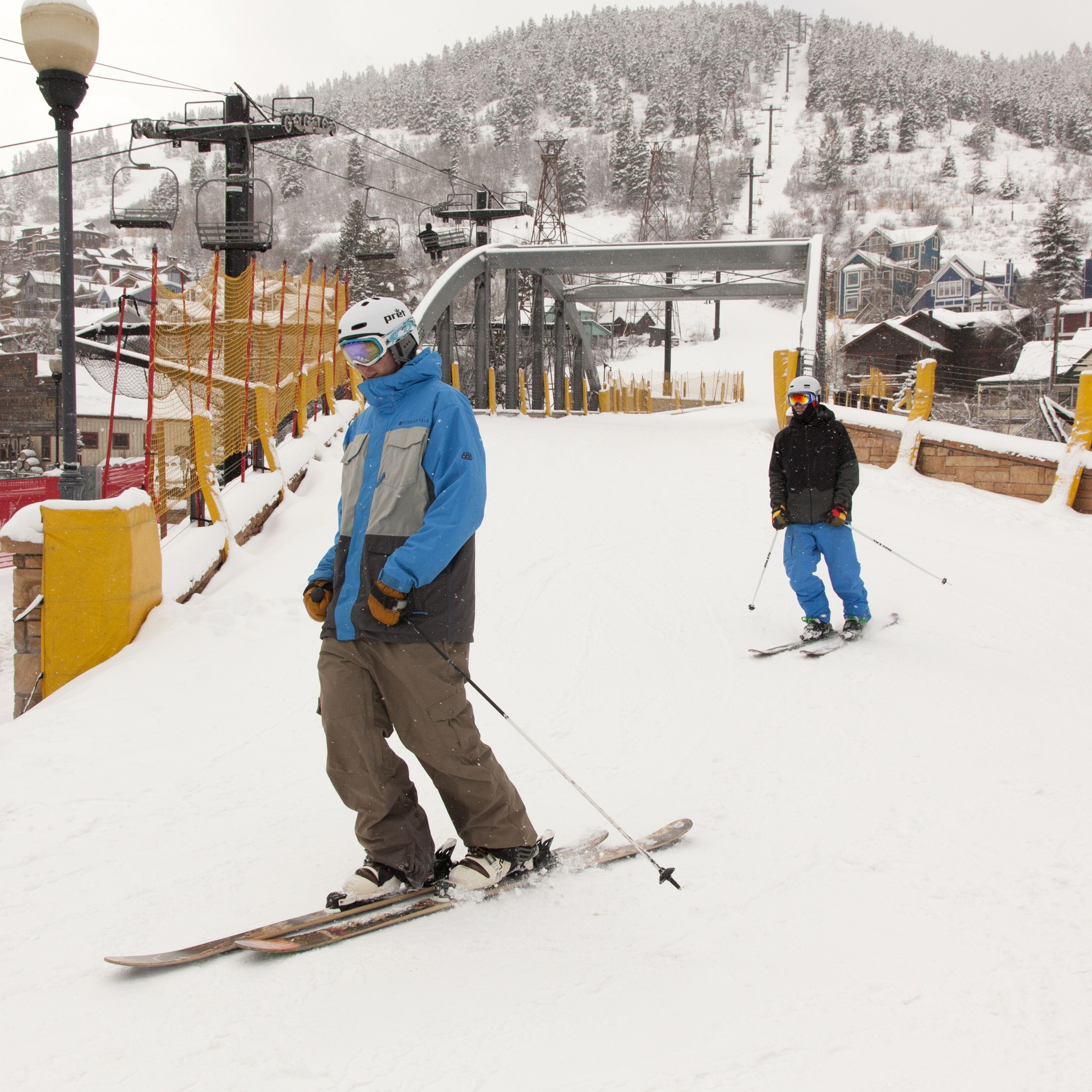 A ski slope with a chairlift, snow-covered trees, and buildings in the background.