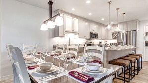 A modern kitchen with white cabinets, stainless steel appliances, and pendant lighting.