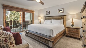 A bedroom with a bed, a ceiling fan, a nightstand, a dresser, and a view of the outdoors. - Snow Flower 056 3 Bedroom Condo by RedAwning (Park City)