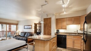 Cocina compacta con armarios de madera, lavavajillas integrado y encimera de granito.