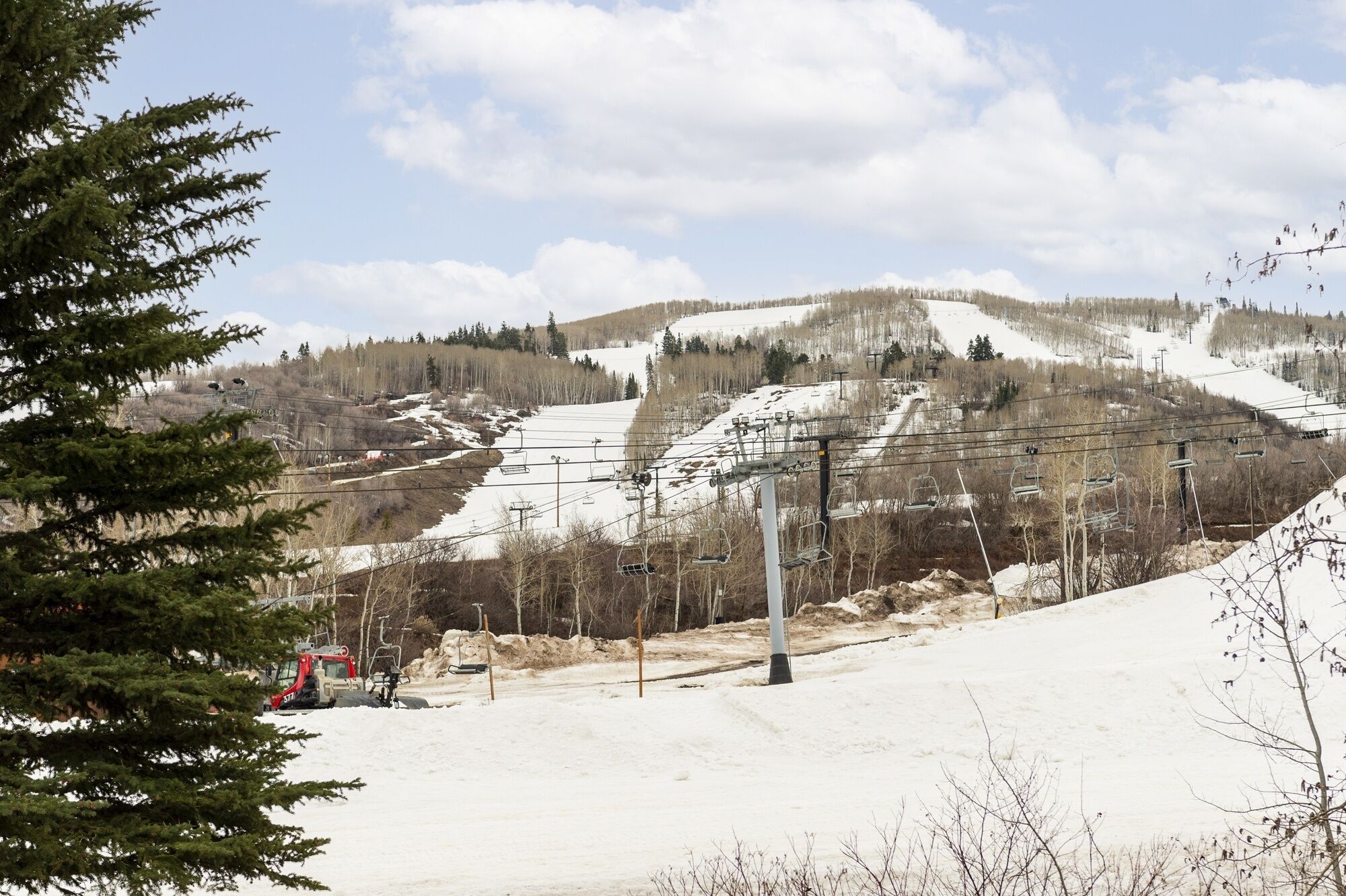 A ski resort with a chairlift, snow-covered slopes, and a forested mountain backdrop.