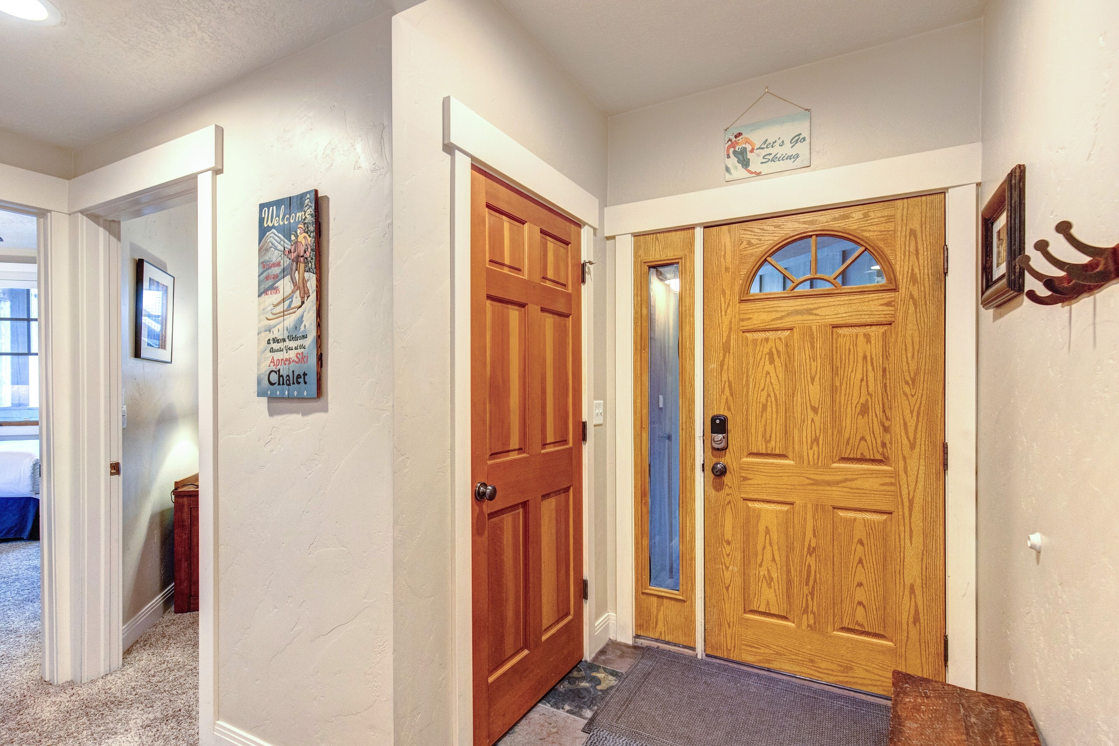 A hallway with a wooden door, a blue door, and a welcome sign.