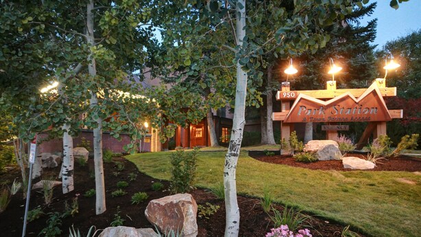 A well-maintained garden with large rocks, a wooden sign for Park Station & Town Center Access, and a building entrance with lights. - Park Station 233 2 Bedroom Condo by RedAwning (Park City)