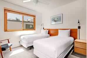 A bedroom with two beds, a wooden nightstand, a desk, and a chair. - Snow Flower 029 6 Bedroom Condo by RedAwning (Park City)