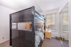 A bunk bed with a wooden frame, a bedside table with a lamp, and a window with blinds. - Snow Flower 146 2 Bedroom Condo by RedAwning (Park City)