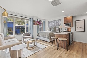 A modern, well-lit room with a bed, a small kitchen area, and a seating area with a sofa and a round table. - Galleria 307-studio 1 Bedroom Home by RedAwning (Park City)