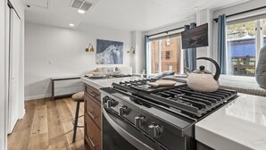 Une cuisine moderne équipée d’une cuisinière à gaz, d’une bouilloire et d’un coin repas avec une table et des chaises.