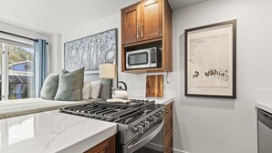 Une cuisine moderne équipée d’une cuisinière à gaz, d’un four à micro-ondes et d’un four traditionnel. Une fenêtre offre une vue sur un immeuble bleu.