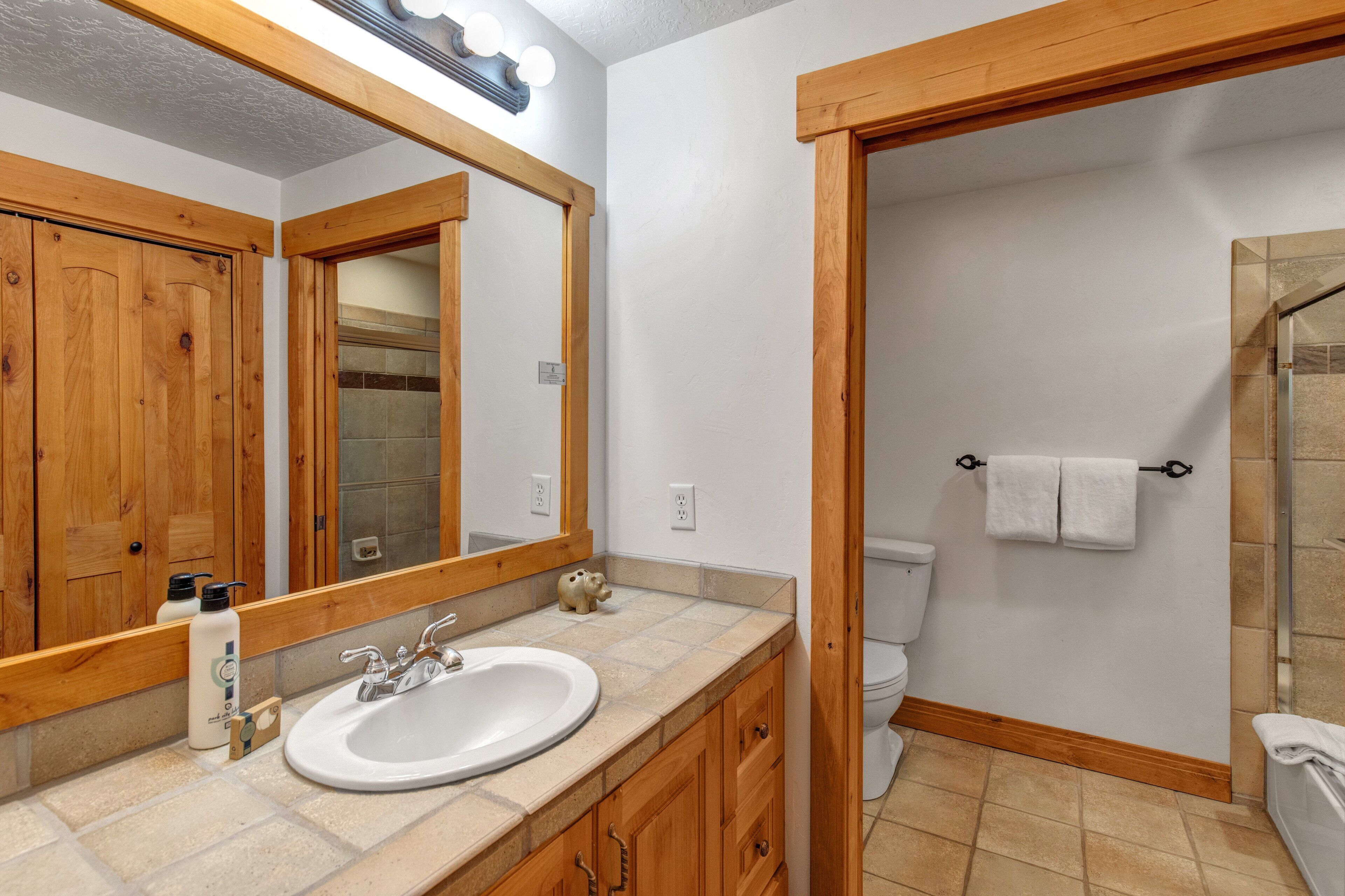 A bathroom with a wooden vanity, a large mirror, a sink, and a shower area.
