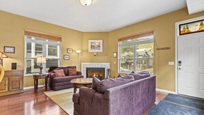 A living room with a fireplace, wooden flooring, and a large window.