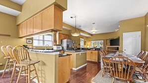 A spacious kitchen with wooden cabinets, a central island, and a dining area with wooden chairs.