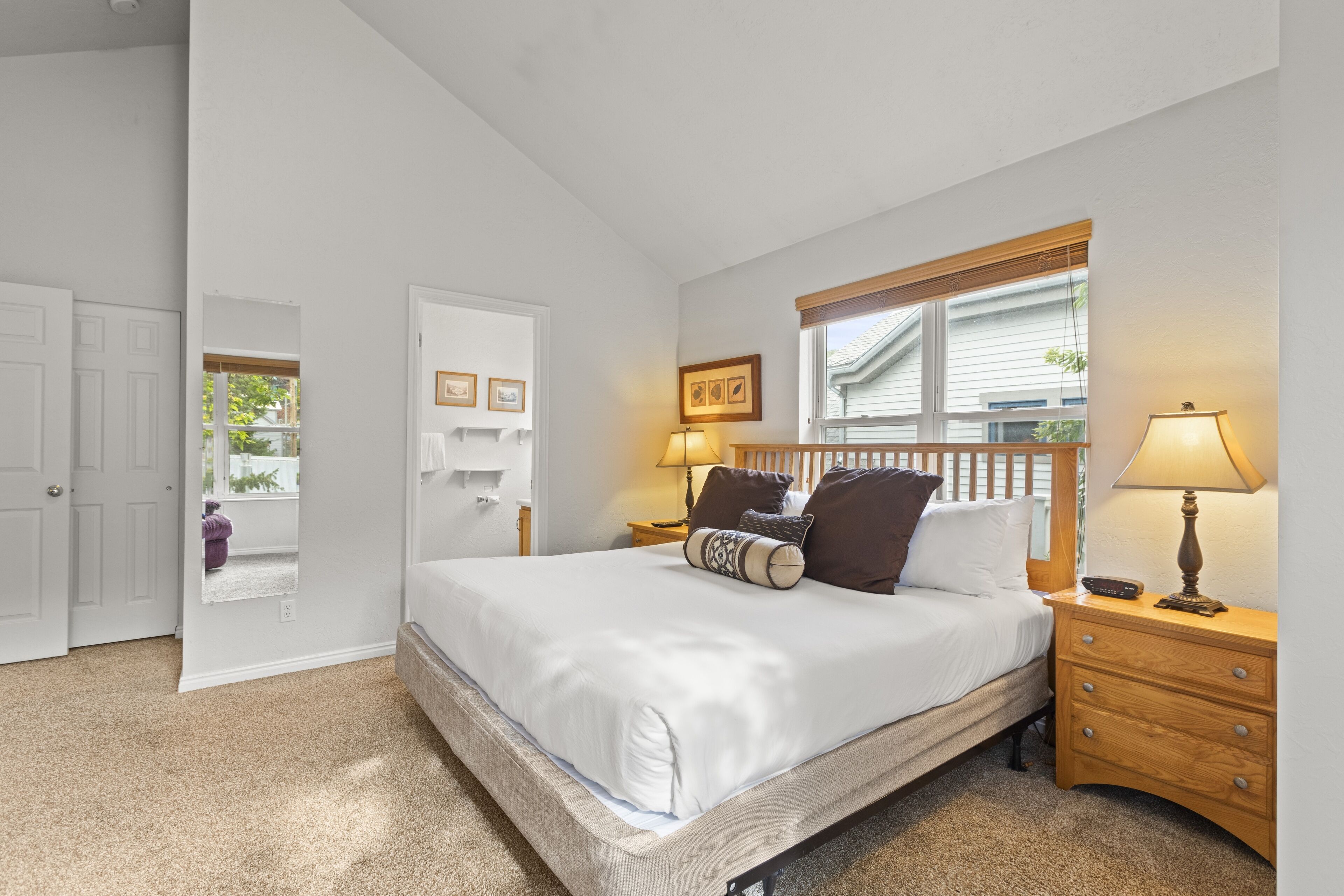 A bedroom with a bed, bedside tables, a window, and a door.