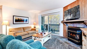 A living room with a sofa, a coffee table, a fireplace, and a large window. - Snow Flower 150 2 Bedroom Condo by RedAwning (Park City)