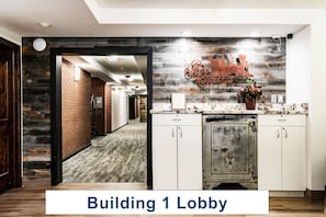 A lobby with a wooden floor, a brick wall, a vintage-style refrigerator, and a decorative sign.