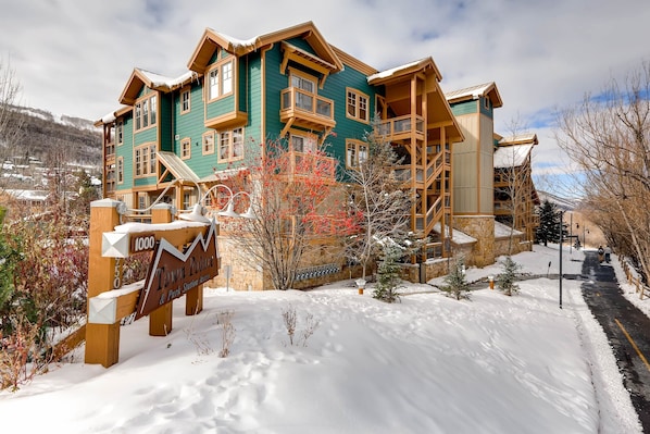 A multi-story building with a green facade and wooden balconies, surrounded by snow.