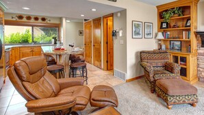 A spacious living room with a leather sofa, a patterned armchair, and a wooden cabinet with a plant. - Racquet Club 60 2 Bedroom Condo by RedAwning (Park City)