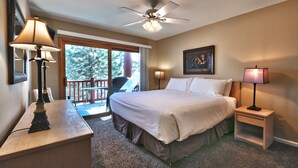 Ein Hotelzimmer mit einem Bett, einem Schreibtisch, einem Sessel, einem Deckenventilator, einem Fenster und einer Tür, die auf einen Balkon führt.