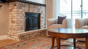 A living room with a stone fireplace, a round wooden coffee table, and a beige sofa.