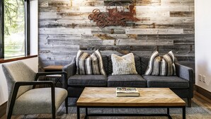 A modern living room with a grey sofa, striped pillows, and a rustic wall with a 'Park Station' sign.