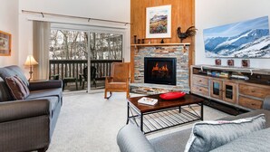 A cozy living room with a fireplace, a large window, and a view of the outdoors.