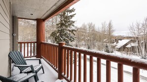 Un balcon abrité, doté de balustrades en bois et de deux fauteuils Adirondack.