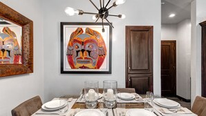 A dining area with a wooden table set for six, framed artwork above, and a modern chandelier. - Lift Lodge 102 3 Bedroom Condo by RedAwning (Park City)