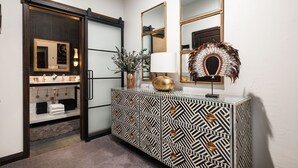 A modern bathroom with a vanity, mirrors, and a decorative wall piece.