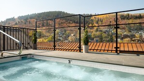 A rooftop pool with a view of a forested hillside and residential buildings.