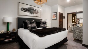 A modern bedroom with a large bed, a black and white patterned dresser, a green floor lamp, and a feather artwork on the wall. - Lift Lodge 102 3 Bedroom Condo by RedAwning (Park City)