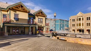 A wooden boardwalk leading to a row of colorful buildings with shops on the ground floor.