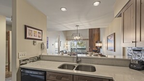 A modern kitchen with a double sink, dishwasher, and a blender on the counter. - Snow Flower 127 2 Bedroom Condo by RedAwning (Park City)