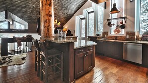A spacious kitchen with dark wood cabinets, a large island with bar stools, and a rustic ceiling.