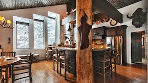 A rustic kitchen with wooden floors, a central island, and a large wooden pillar.