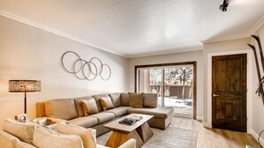 A modern living room with a sectional sofa, a coffee table, and a wall-mounted circular light fixture.
