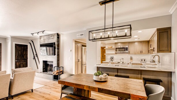 A modern kitchen with a wooden dining table, built-in appliances, and a large window.