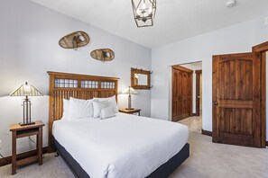 A bedroom with a large bed, wooden headboard, two bedside lamps, and a mirror on the wall. - Town Pointe B304 4 Bedroom Condo by RedAwning (Park City)