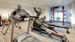 Ett gym med konditionsmaskiner, styrketräningsutrustning och en yogamatta.