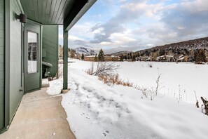 Situated in a serene snowy landscape, this property offers a peaceful retreat with a covered porch and a view of distant mountains.