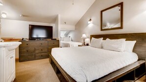 A bedroom with a large bed, a dresser, a television, and a mirror.