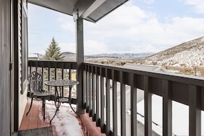 A balcony with a view of snow-covered mountains and a clear sky.