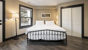 Un dormitorio con cama, ventana, lámpara de pie, un cuadro y un conjunto de puertas.