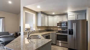 Una cocina moderna con encimeras de granito, electrodomésticos de acero inoxidable y armarios grises claros.