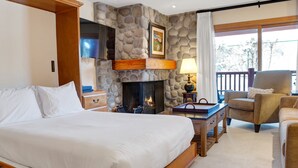 Une chambre avec une cheminée en pierre, un lit, une chaise et une vue sur l’extérieur.