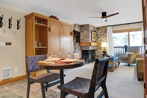 A dining area with a stone fireplace, wooden cabinets, and a ceiling fan.