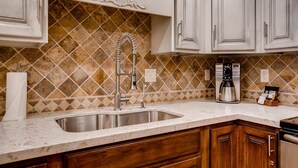 A kitchen with a stainless steel sink, wooden cabinets, and a decorative backsplash. - Park Station 140 2 Bedroom Condo by RedAwning (Park City)